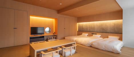 A modern hotel room with a wooden ceiling, a flat-screen TV, a bed with white bedding, and a wooden table with benches.