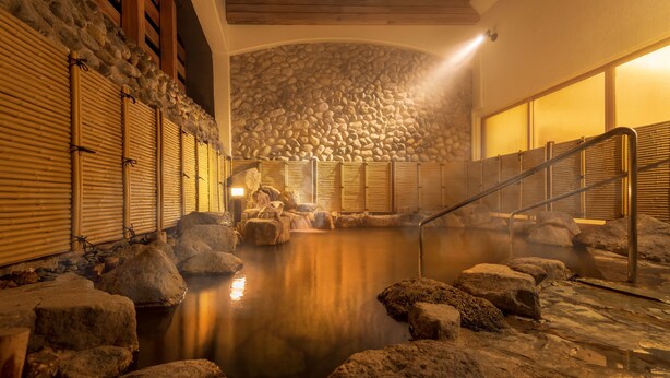 A hot spring bath area with stone walls, wooden railings, and a central water feature. - Lime Resort Myoko (Myoko)