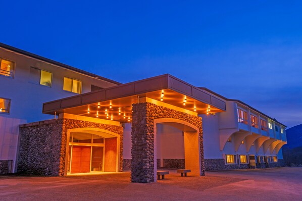 Hotel com fachada de pedra, entrada coberta e várias varandas.