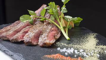 A steak with a garnish of green leaves and herbs, served on a slate plate with a sprinkle of seasoning.