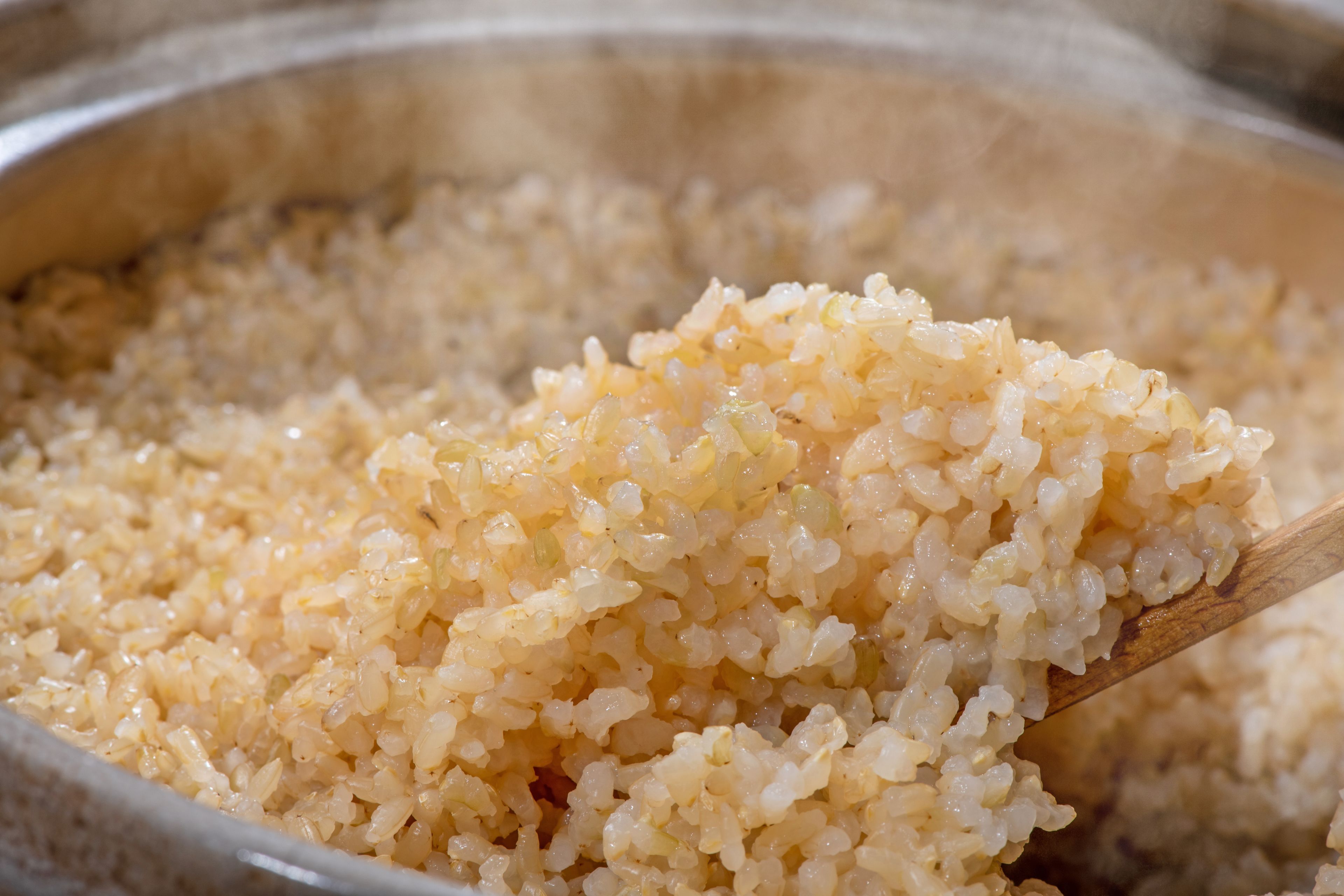 Primer plano de arroz cocido siendo servido con una cuchara de madera.