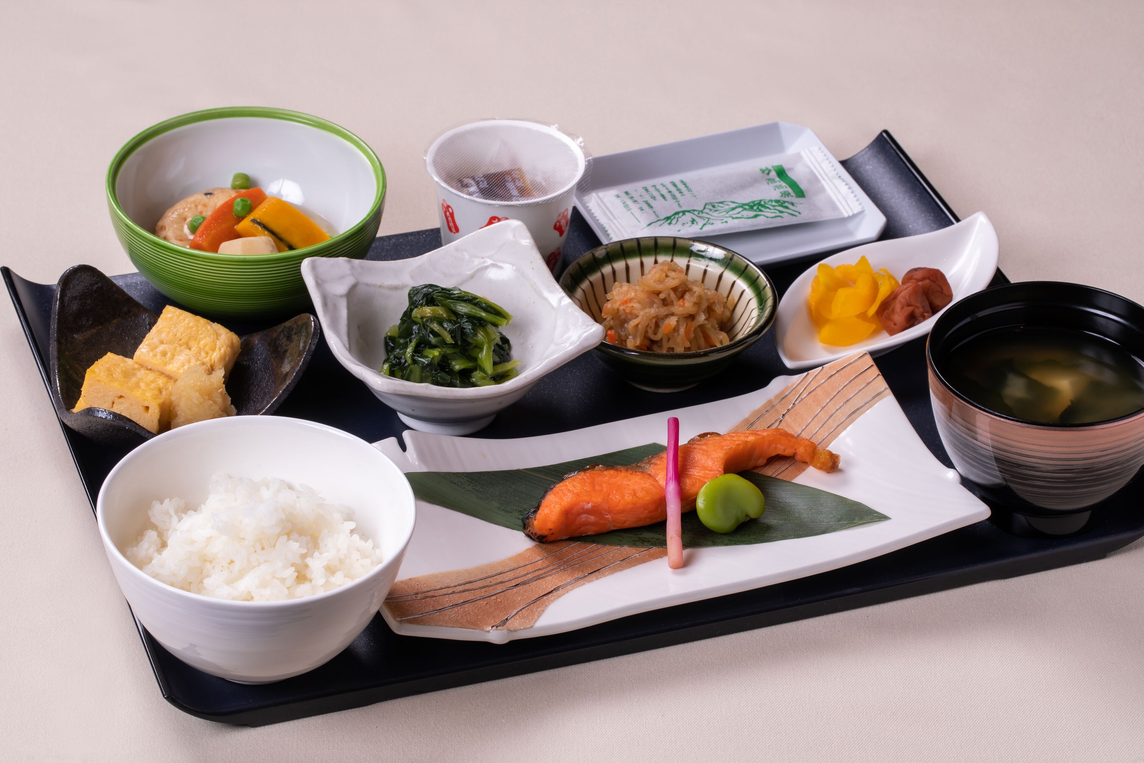 A tray with various Japanese dishes including rice, tofu, vegetables, and fish.