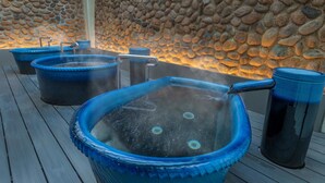 A spa area with multiple hot tubs and a stone wall backdrop. - Lime Resort Myoko (Myoko)