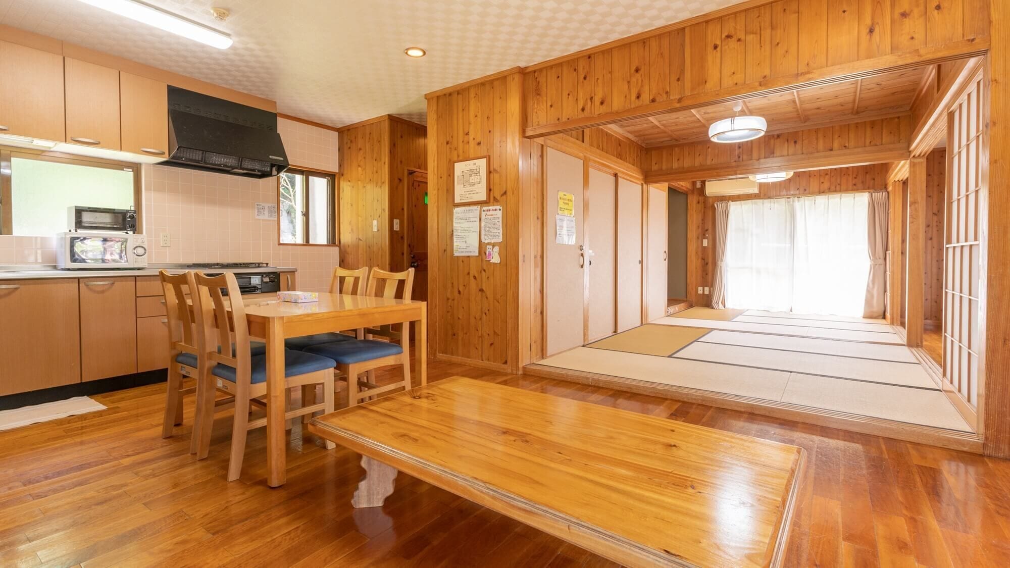 A wooden interior with a kitchen, dining area, and tatami mat room.