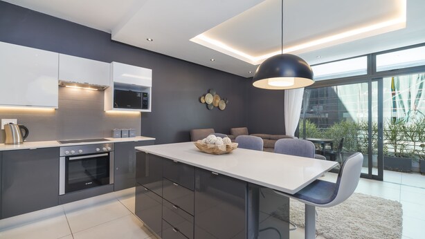 A modern kitchen with a central island, built-in appliances, and a dining area with a view of the outdoors.