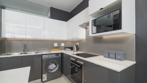 A modern kitchen with a washing machine, oven, and microwave.