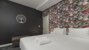 A hotel room with a large bed, a round wall decoration, and a floral wallpaper.