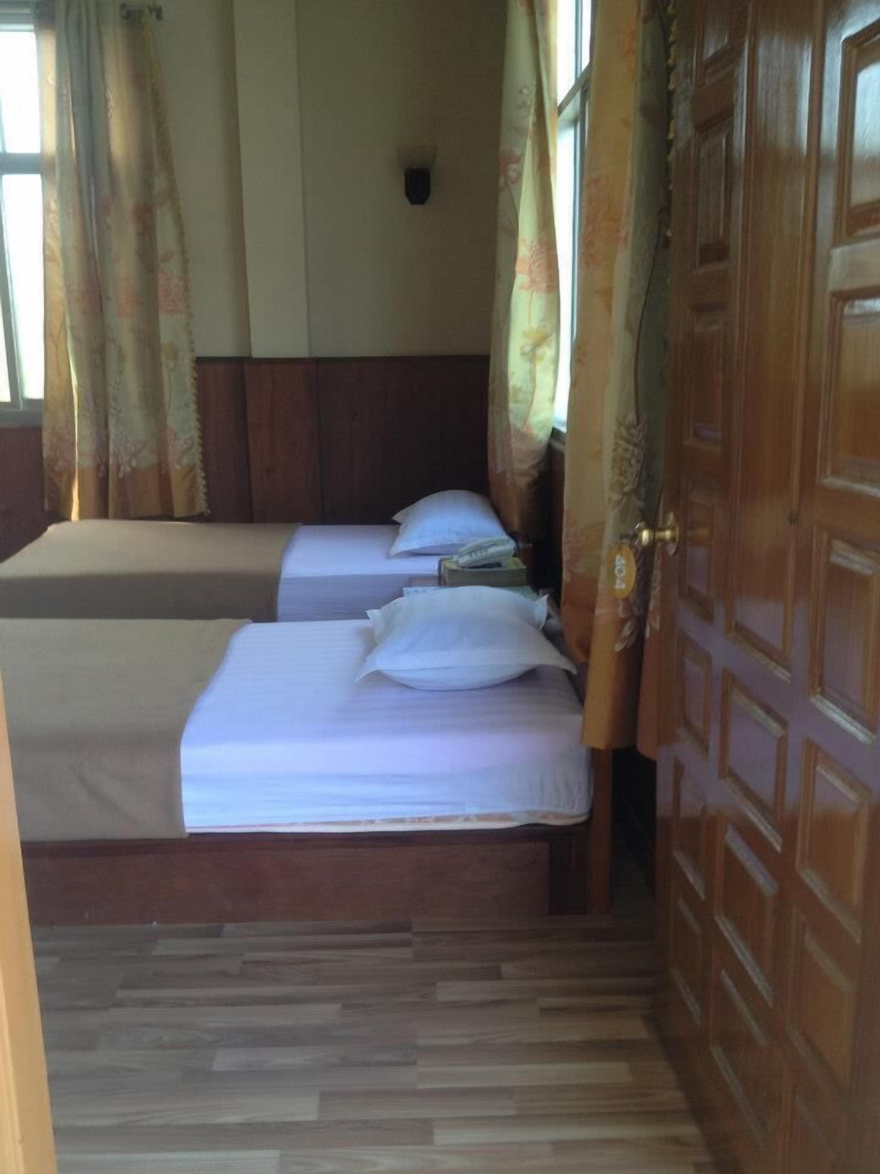 A room with two beds, wooden flooring, and a wooden door.