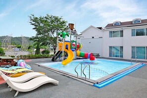 Une piscine avec un toboggan et des chaises longues.