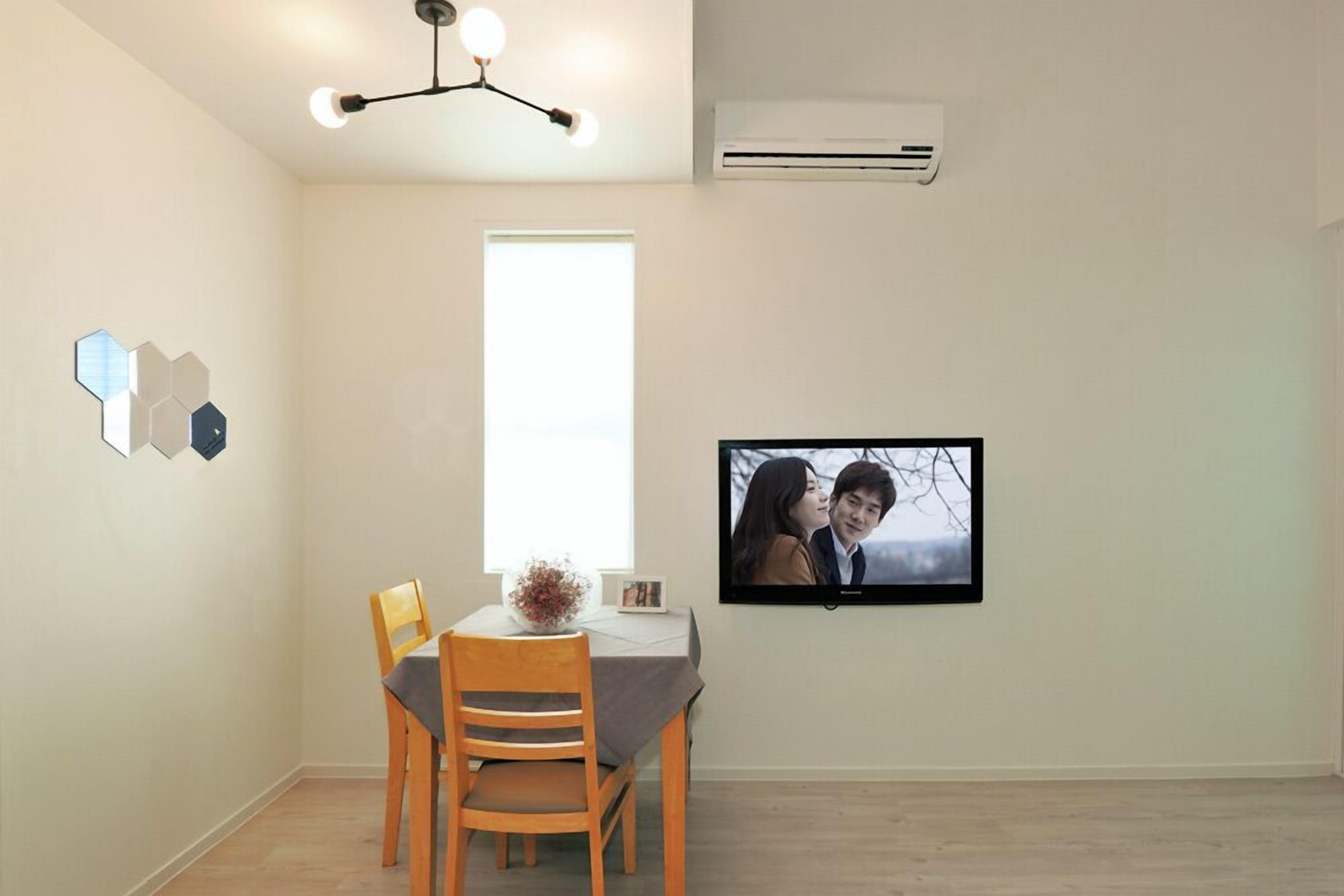 A dining area with a table, chairs, a TV, and a ceiling light fixture.