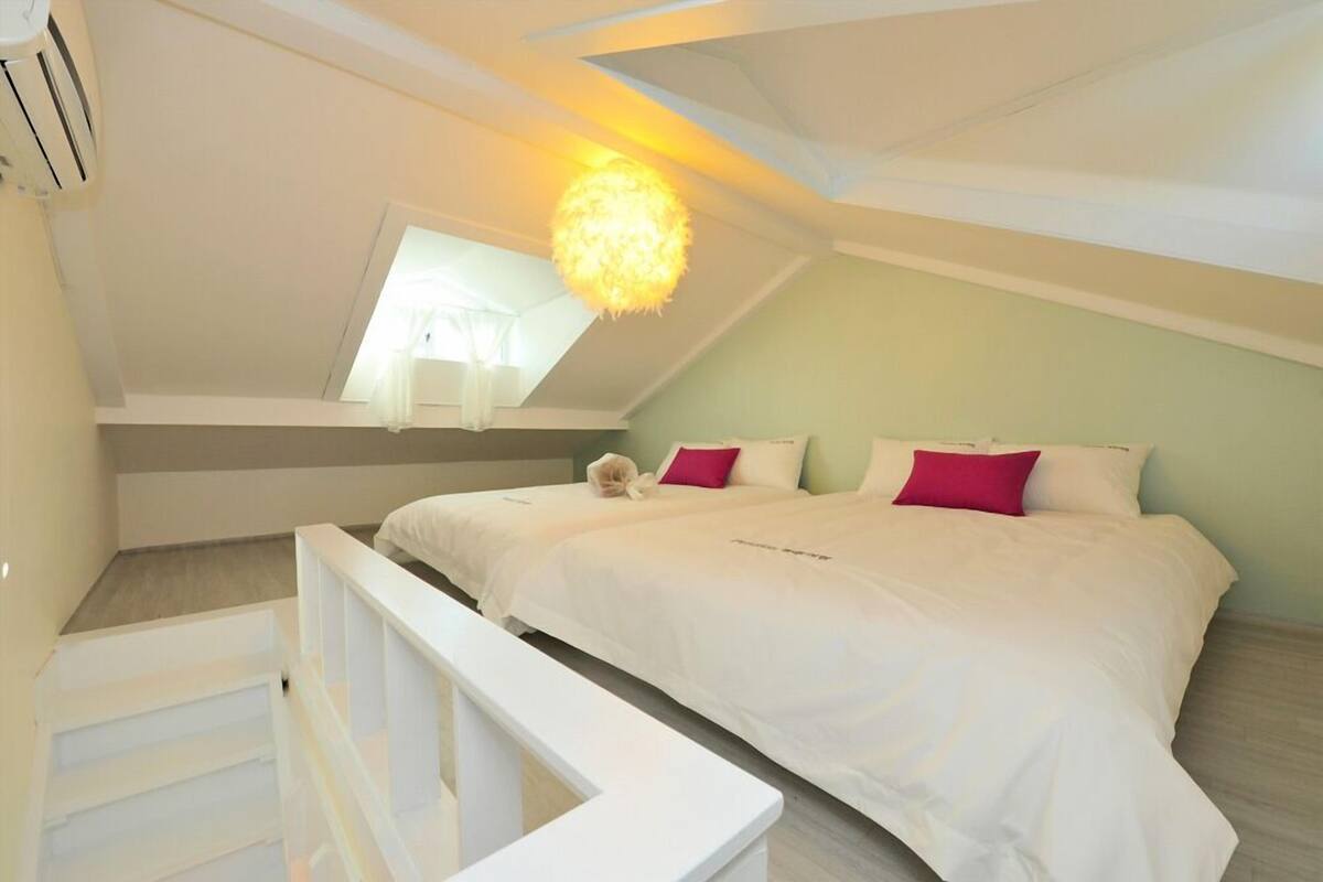 Un dormitorio con una cama grande, ropa de cama blanca y una lámpara esférica original.