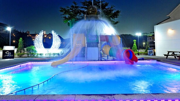 A water park with a large water slide, a fountain, and a pool area.