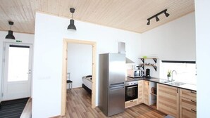 A modern kitchen with stainless steel appliances, wooden cabinets, and a black countertop. - Blue View Cabin 7A with Hot Tub (Bláskógabyggd)