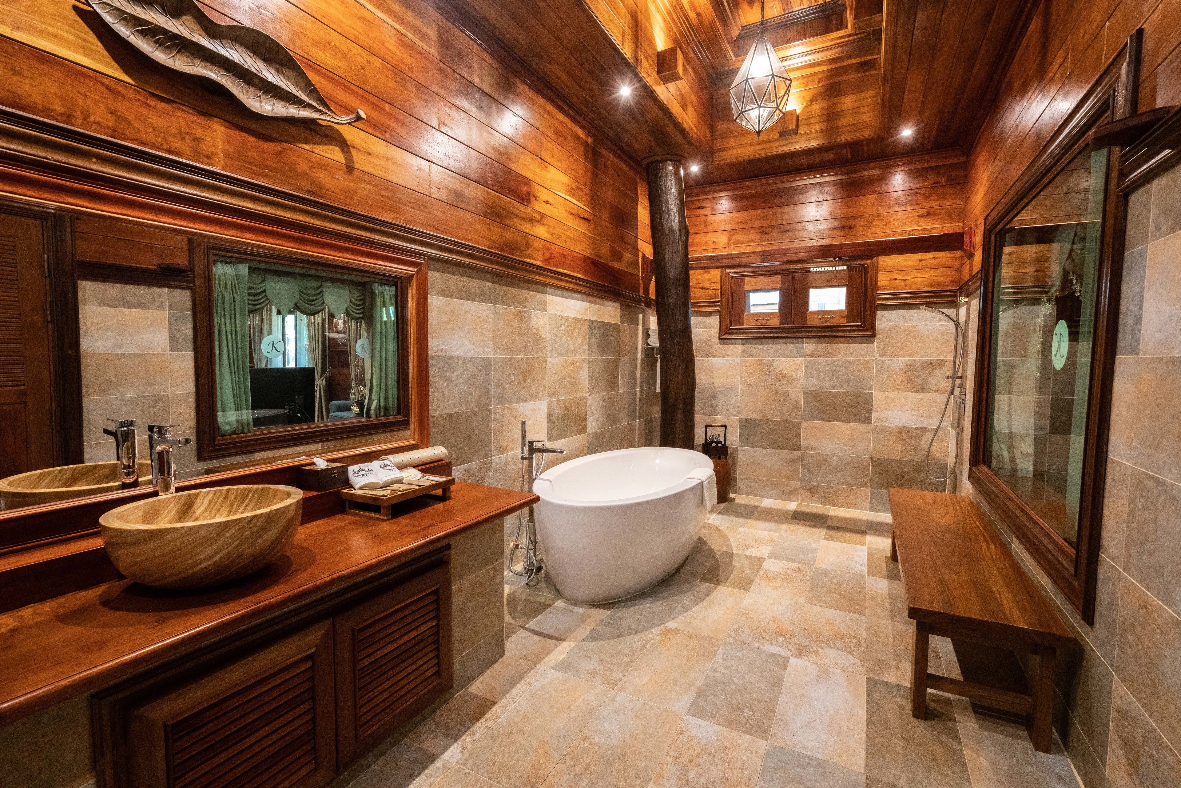 A luxurious bathroom with a large wooden vanity, a freestanding bathtub, and a large mirror.
