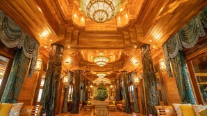 A luxurious lobby with wooden paneling, large chandeliers, and ornate columns. - WandaVista Resort Khum Wang Nuea Chiang Mai (San Kamphaeng)