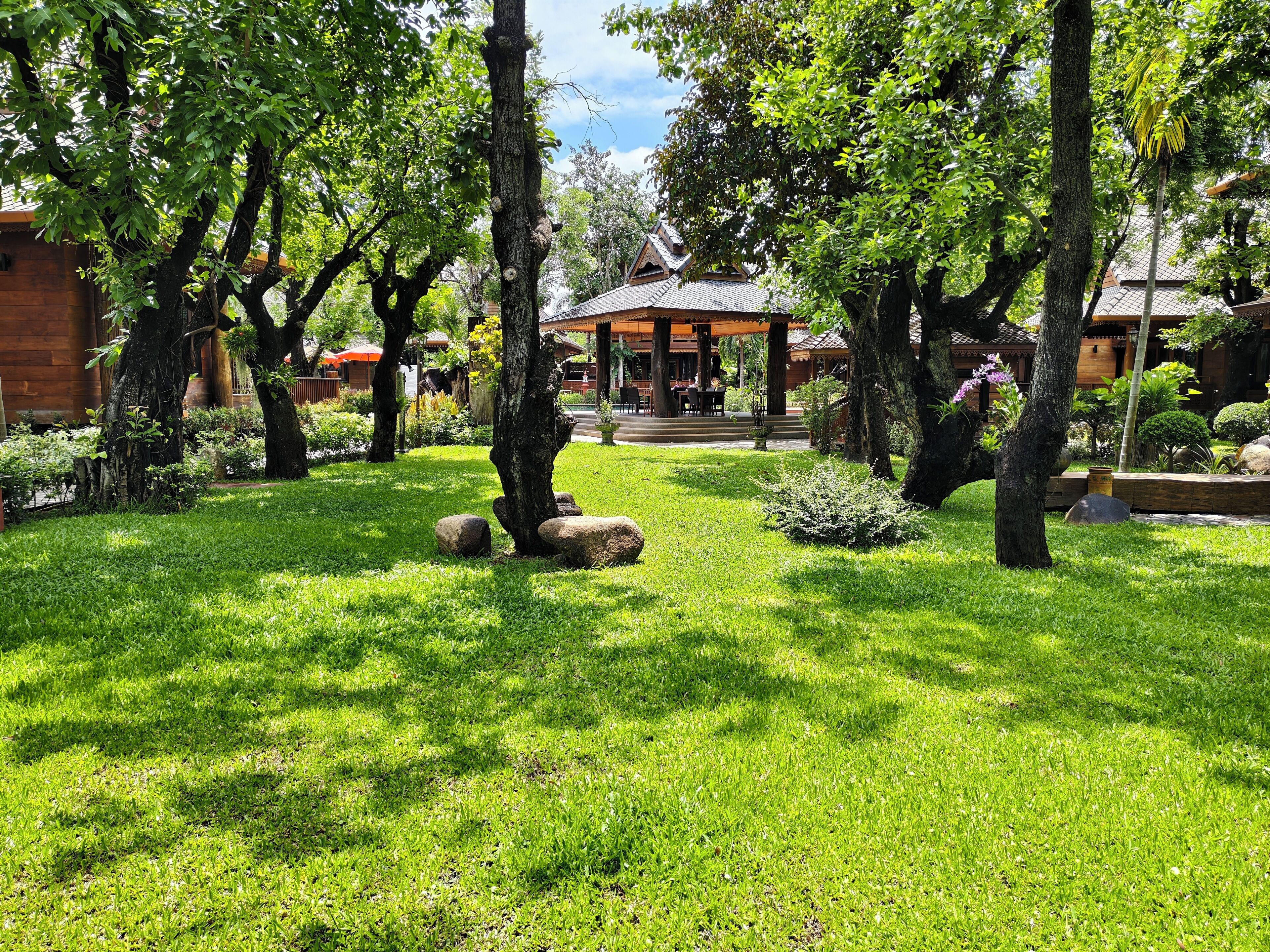 A well-maintained garden with a gazebo, stone pathway, and lush greenery.