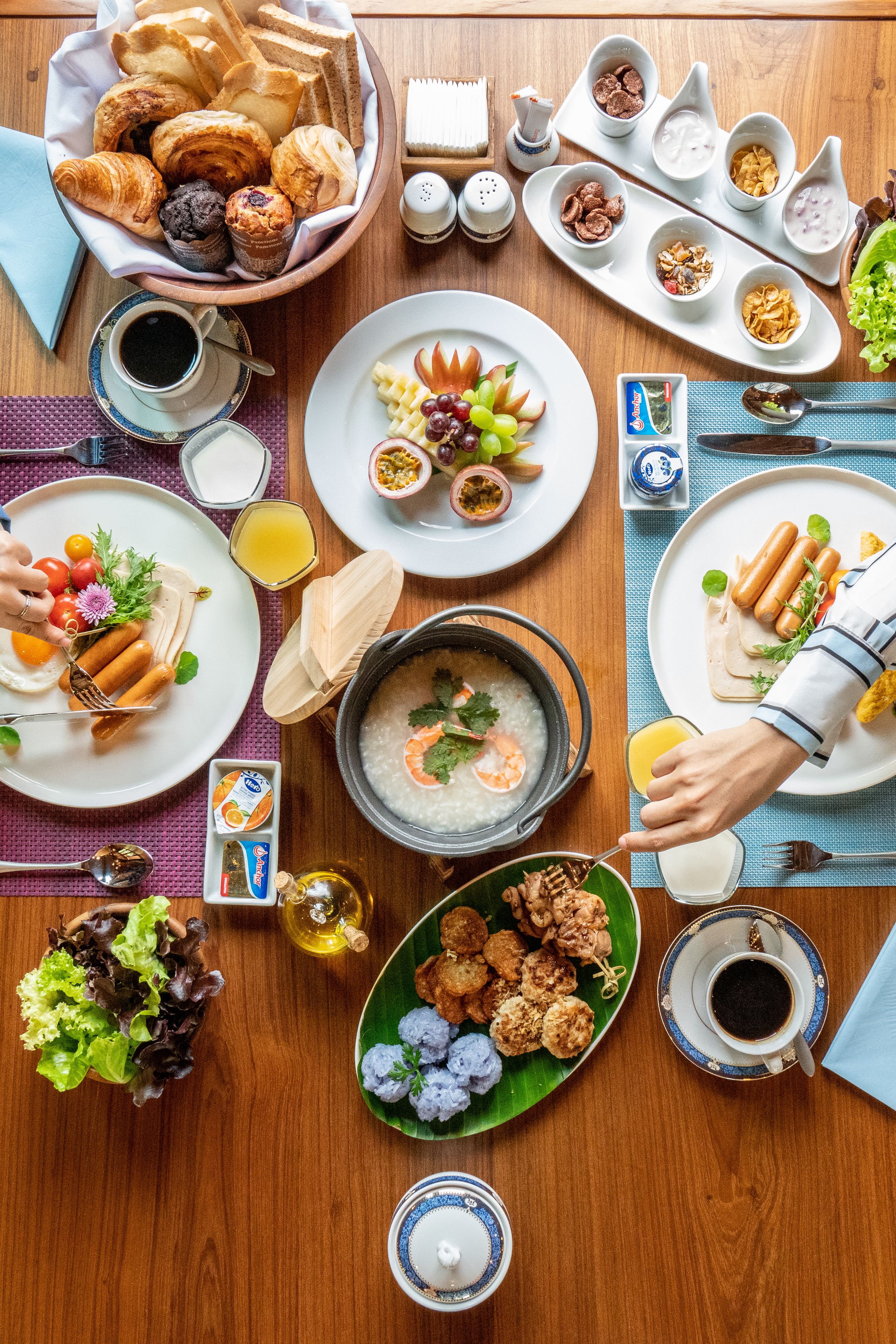 A breakfast buffet with various dishes, including pastries, fruits, and a soup pot.