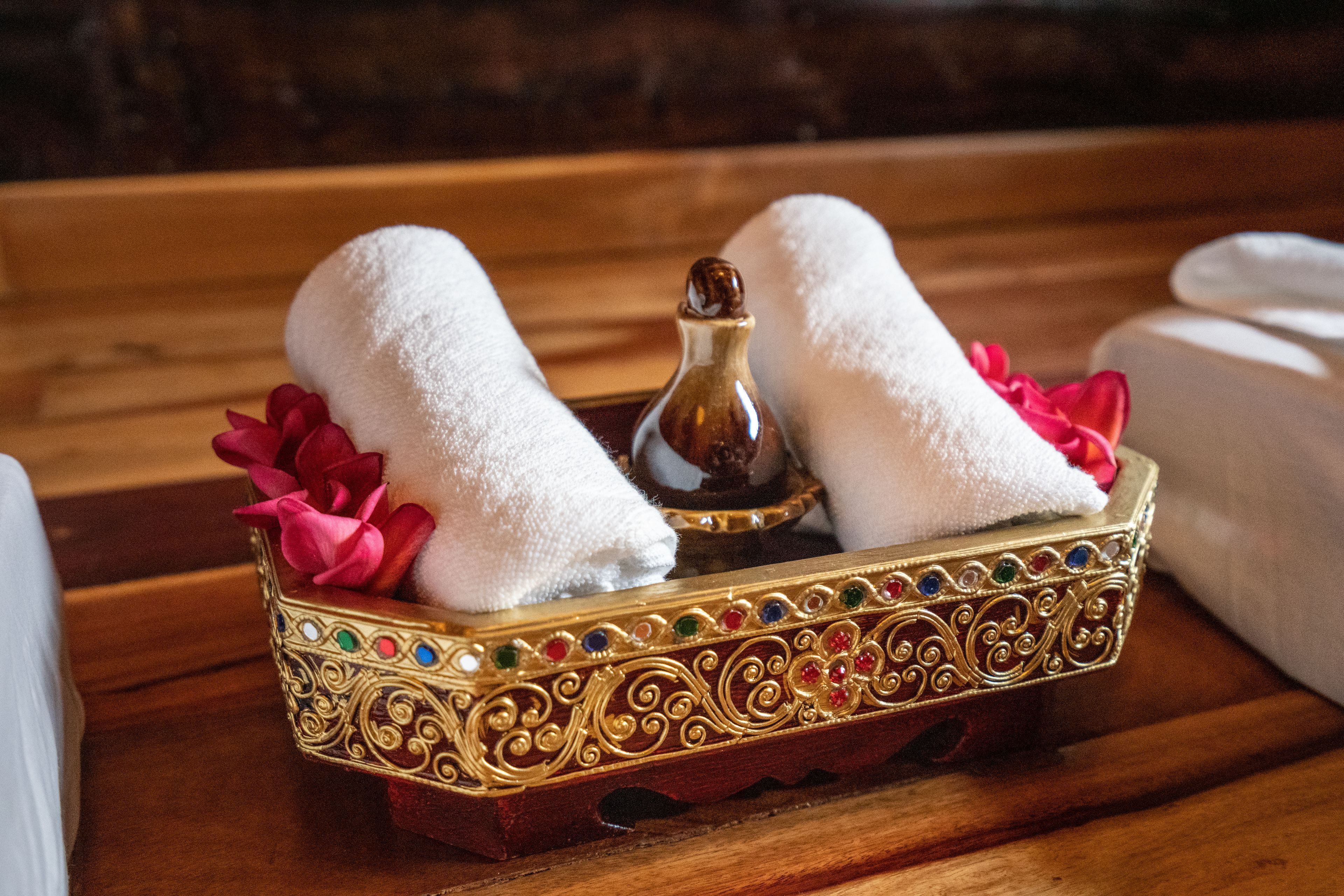 A wooden tray with two white towels and a decorative item.