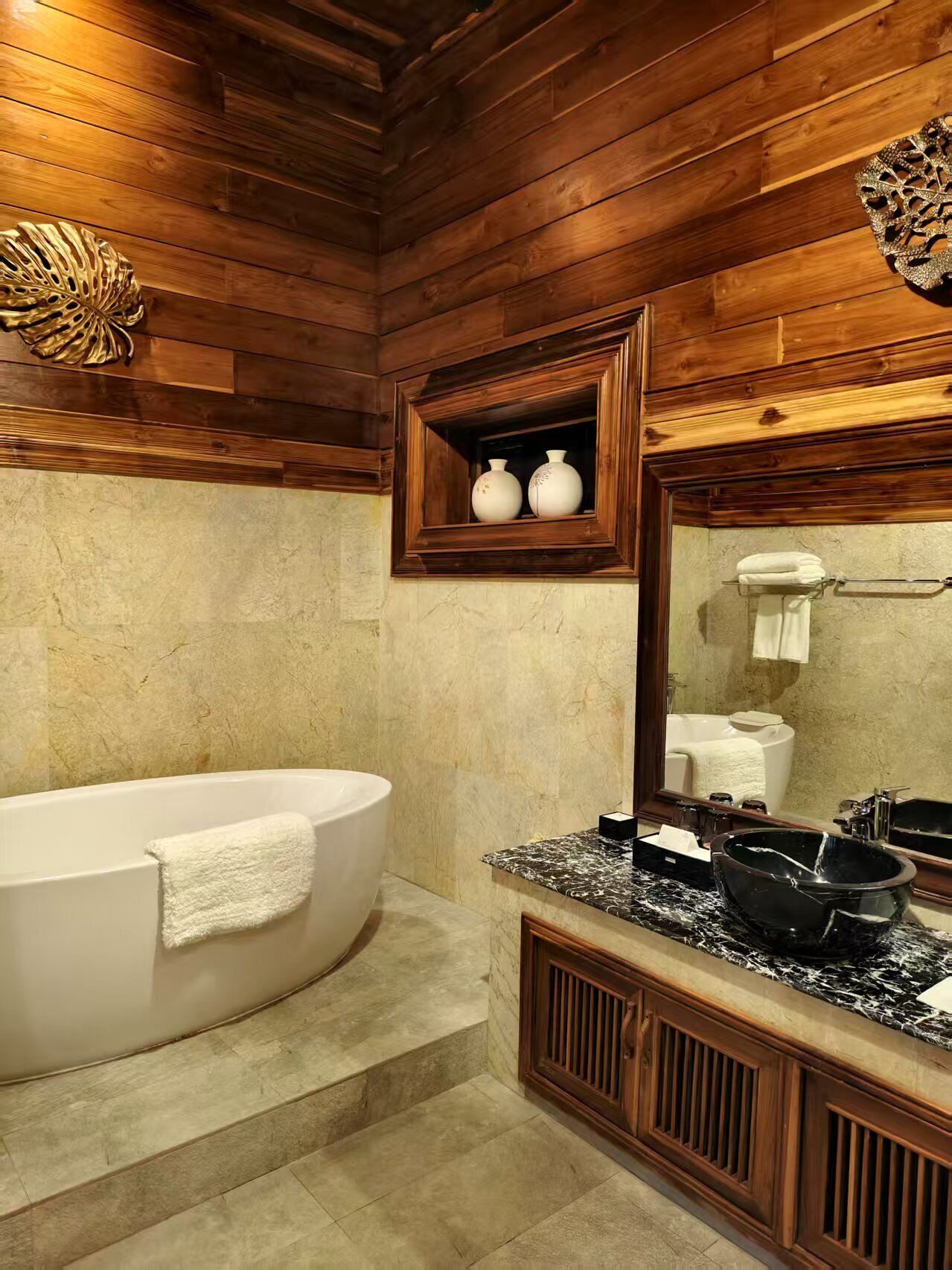 A bathroom with a freestanding bathtub, marble countertops, and a wooden ceiling.