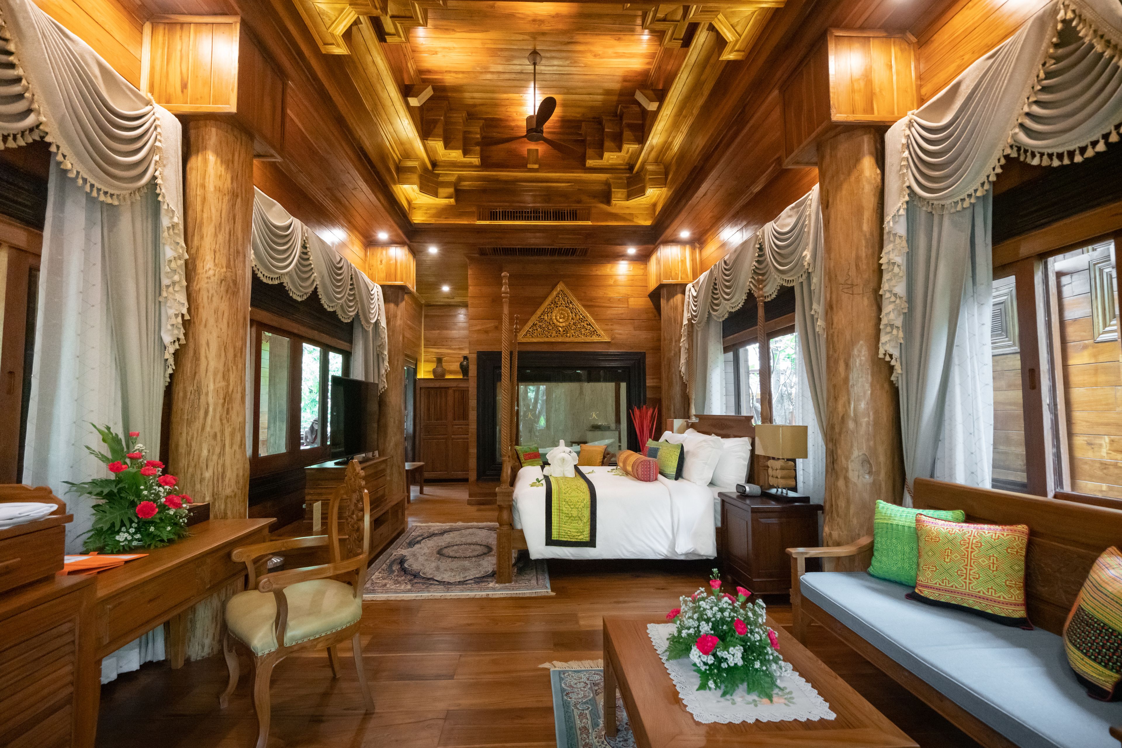 A wooden interior with a bed, sofa, and desk area.
