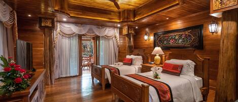 A wooden-themed bedroom with two beds, a chandelier, and a decorative wall piece.