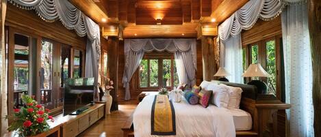 Un dormitorio espacioso con una cama grande, techo de madera y un televisor sobre un mueble de madera.