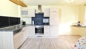 Una cocina moderna con alacenas de madera clara, una estufa de acero inoxidable y un horno empotrado.