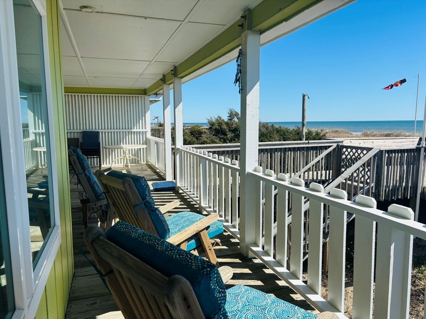 A covered outdoor seating area with wooden chairs and a view of the beach.