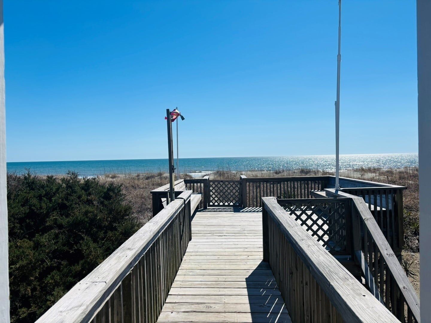 A wooden boardwalk leading to a beach with a clear view of the ocean.