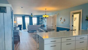 Uma cozinha moderna com armários brancos, uma ilha central e um espaço de refeições com vista.