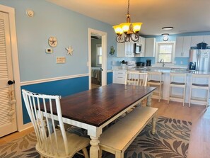 A kitchen with white cabinets, a wooden dining table, and a bench.