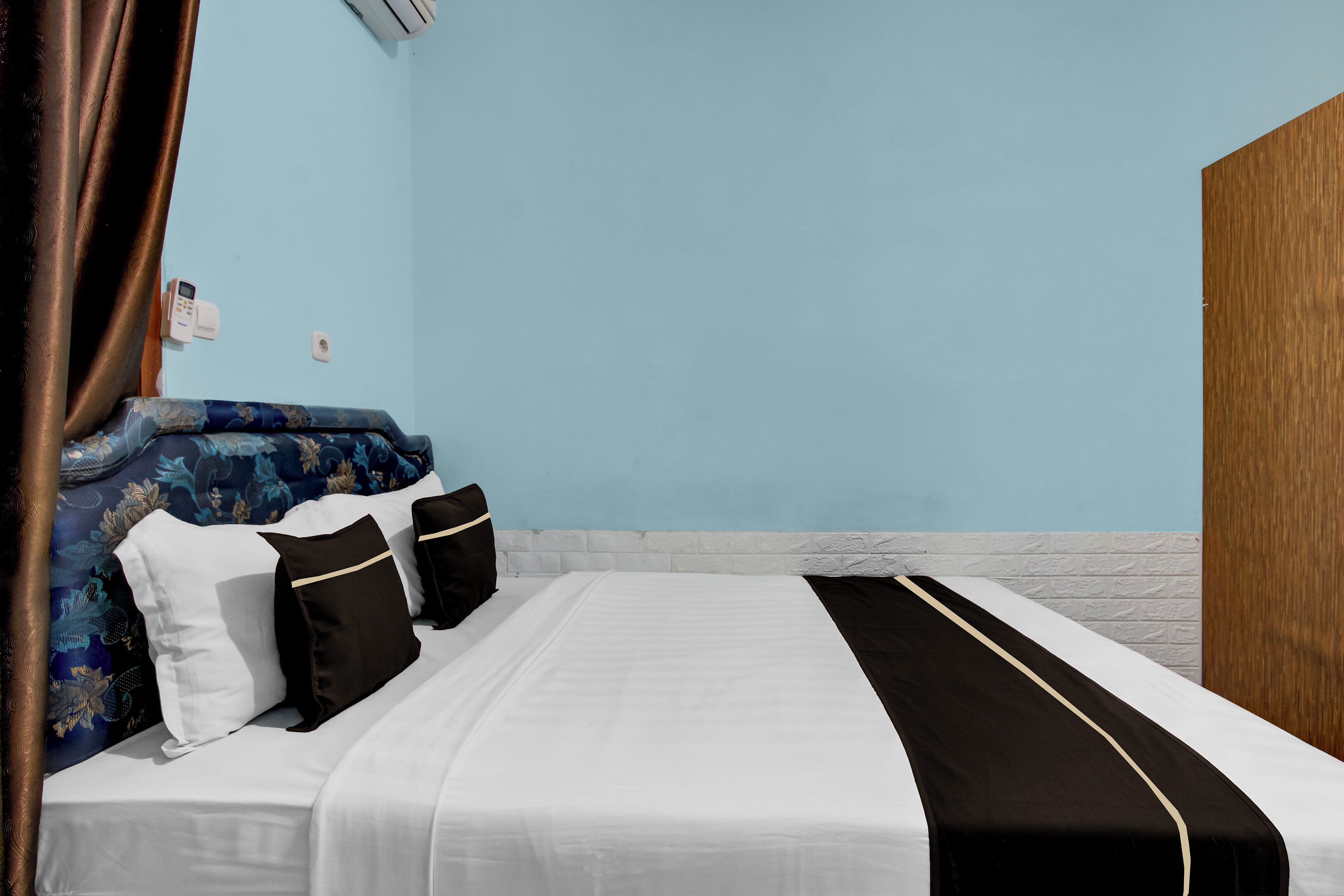 Une chambre d’hôtel avec un lit, un mur bleu et une porte en bois.