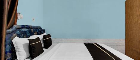 Une chambre d’hôtel avec un lit, un mur bleu et une porte en bois.