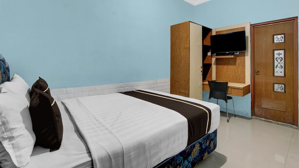 Una habitación de hotel con cama, escritorio, silla y televisión.