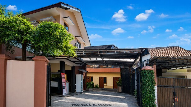 A hotel entrance with a covered walkway, a sign reading 'MENJAI INN,' and a gated driveway. - Hotel O near UGM formerly Bayang Brothers Guest House (Depok)
