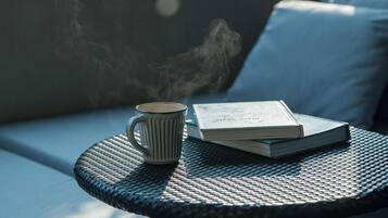 A round metal table with a book and a mug on it.