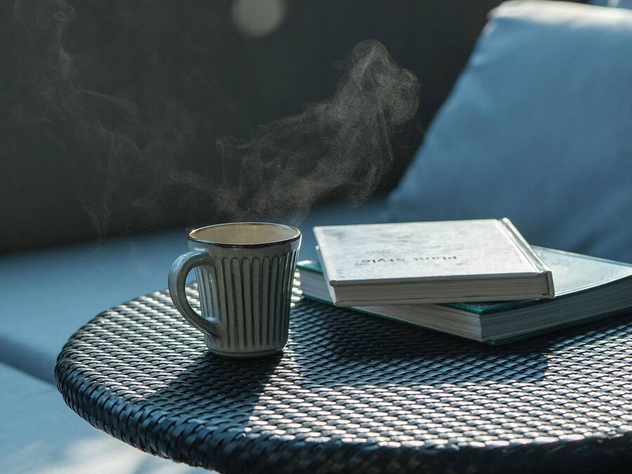 A round metal table with a book and a mug on it.