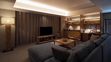 A modern living room with a large flat-screen TV, a sofa, a coffee table, and a lamp.