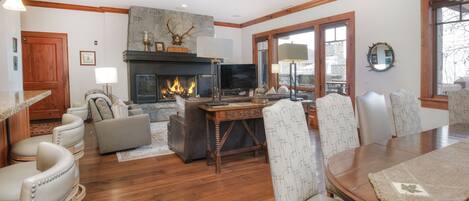 A cozy living room with a fireplace, comfortable seating, and a dining area.