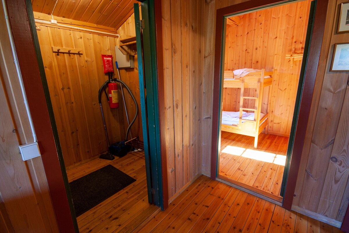Un interior de madera con una litera, un extintor y una puerta que da a otra habitación.