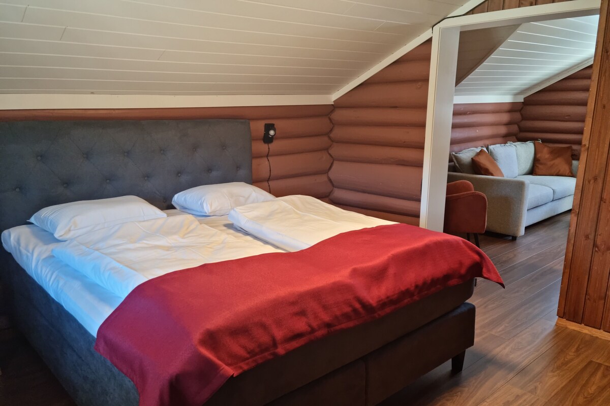 Un dormitorio acogedor tipo cabaña de madera, con cama, sillón y sofá.