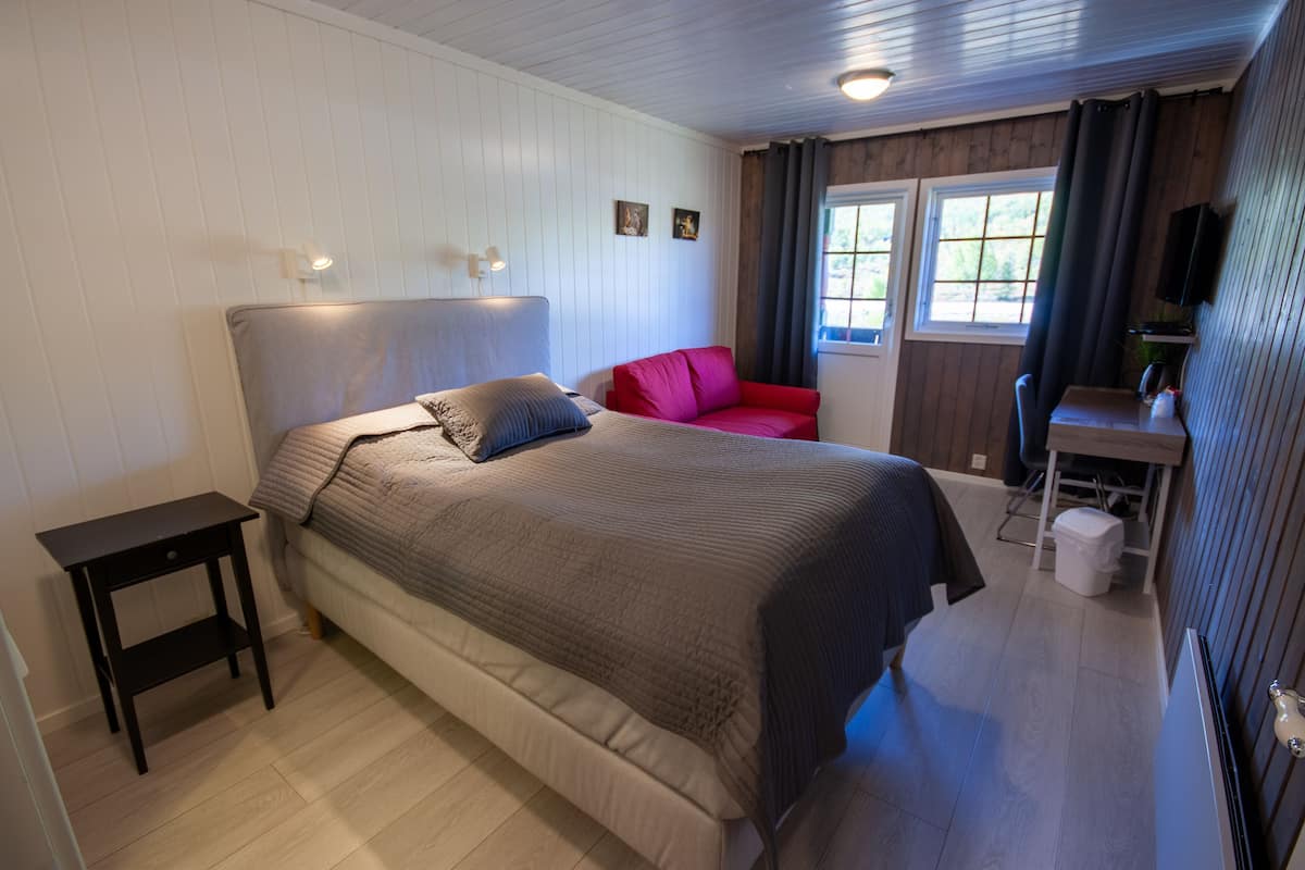 A bedroom with a bed, bedside table, and a desk with a chair.