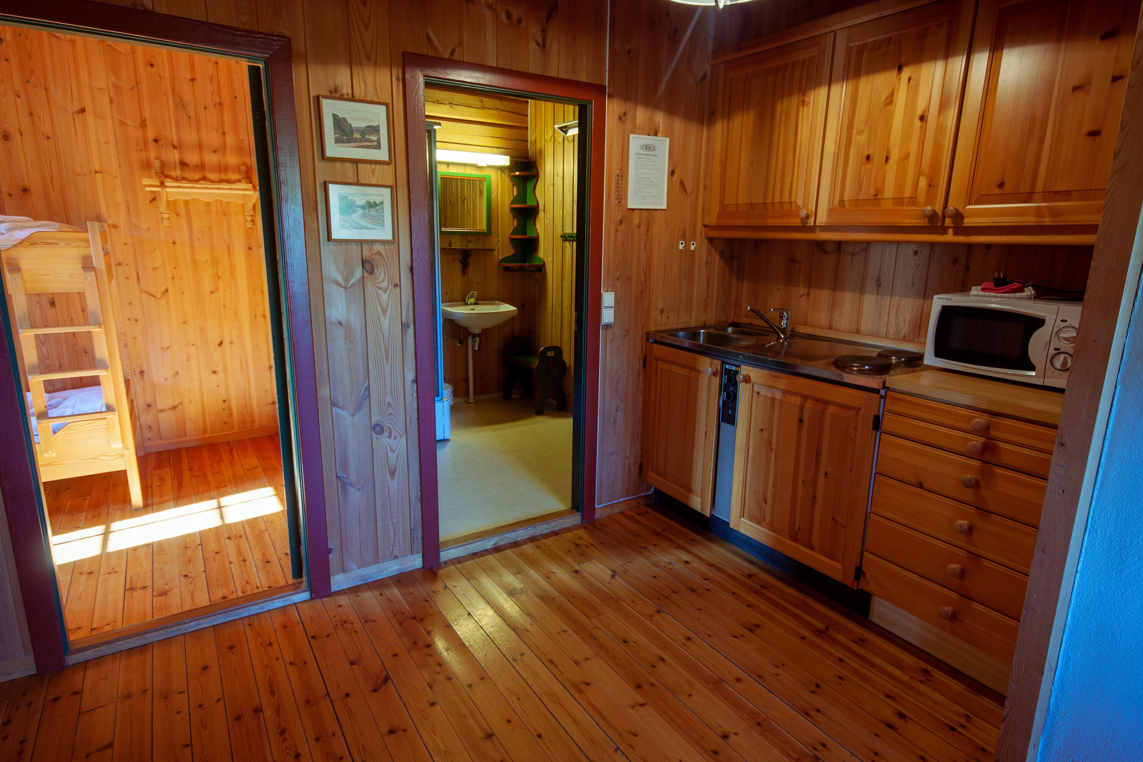 A wooden-paneled kitchen with a sink, microwave, and cabinets.