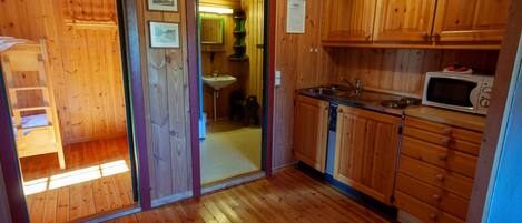 A wooden-paneled kitchen with a sink, microwave, and cabinets.