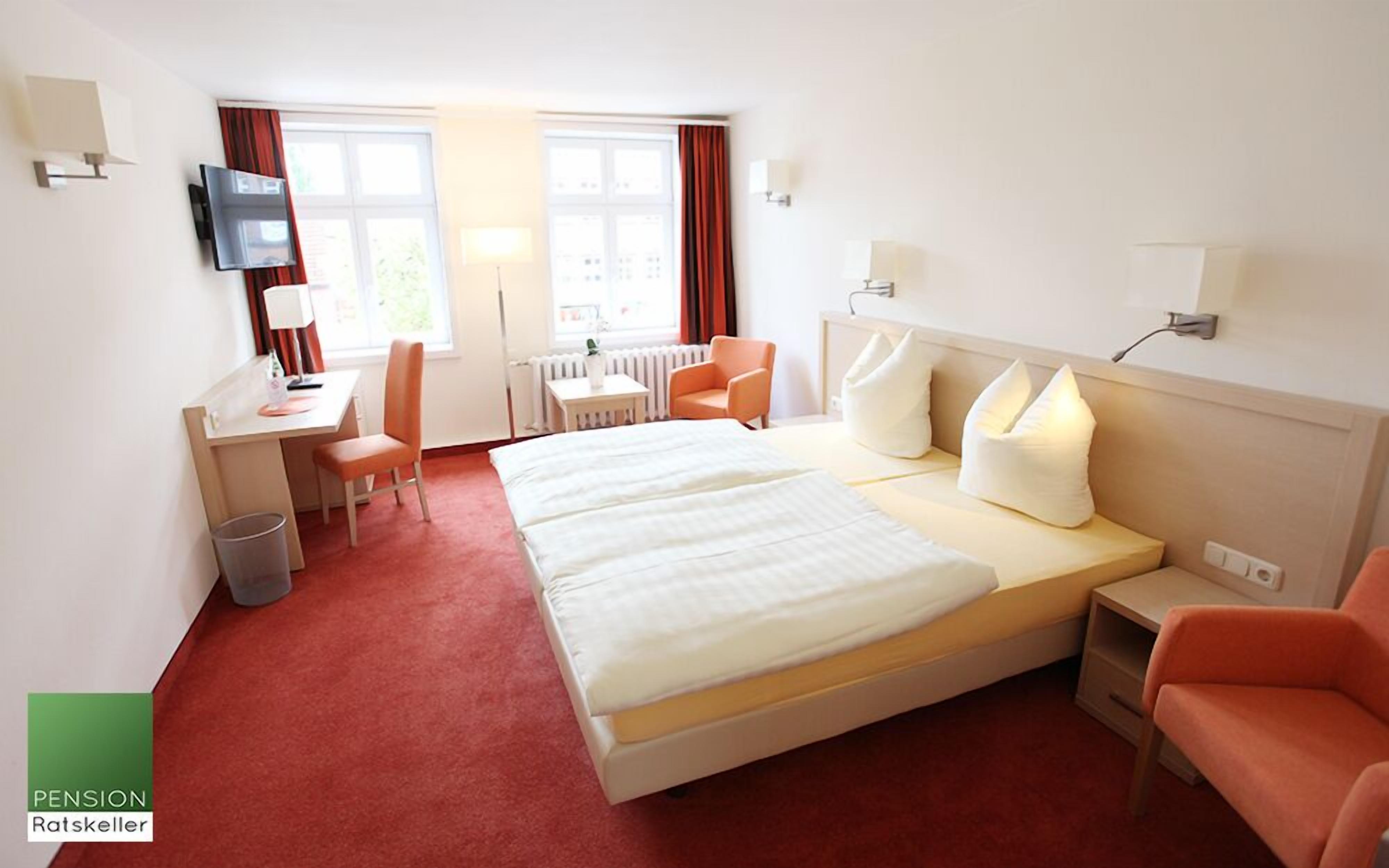 Una habitación de hotel con cama, escritorio, silla y televisor.
