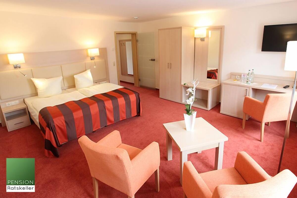 Ein Hotelzimmer mit einem Bett, zwei Stühlen, einem Schreibtisch, einem Spiegel und einem Fernseher.