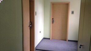 Un couloir avec deux portes en bois, l’une dotée d’une poignée métallique et l’autre d’un trou de serrure.
