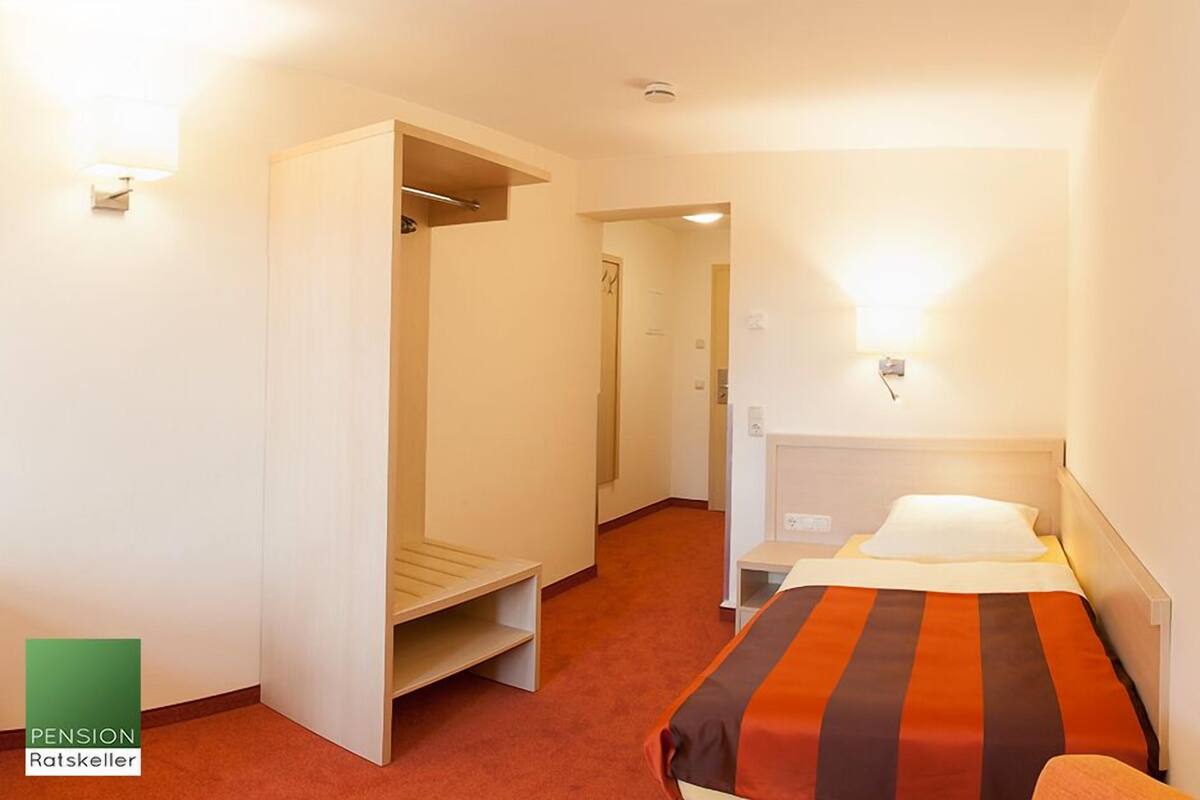 Ein Hotelzimmer mit einem Bett, einem Kleiderschrank, einem Schreibtisch und einem kleinen Tisch.