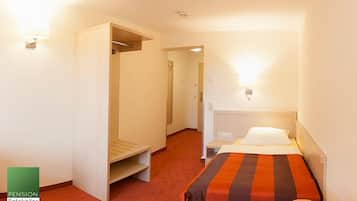 A hotel room with a bed, a wardrobe, a desk, and a small table.