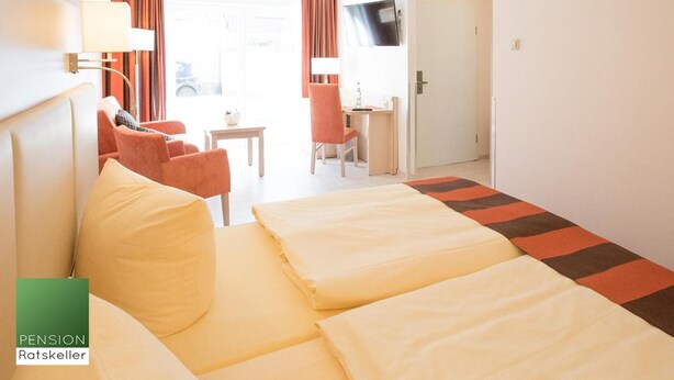 Une chambre d’hôtel avec un lit, deux chaises, une petite table et un téléviseur.
